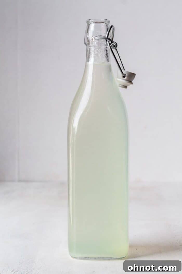 A pitcher filled with water and fresh lime juice, being stirred to combine.