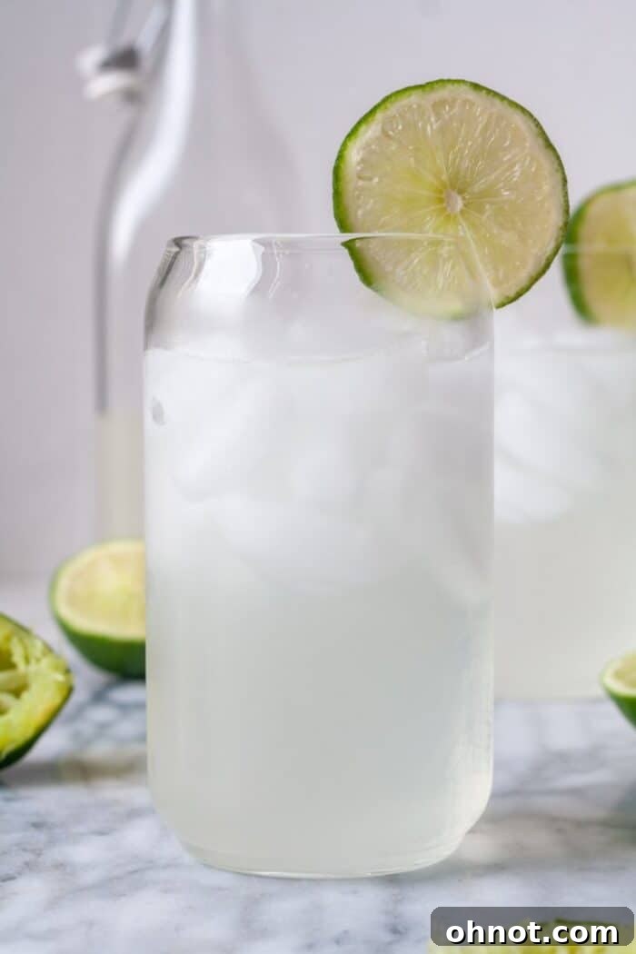 A glass of homemade limeade with ice and a lime slice, ready to drink.