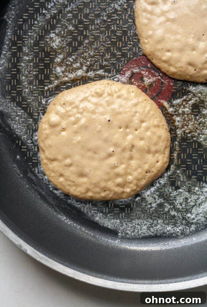 Bubbly oat flour pancakes in skillet