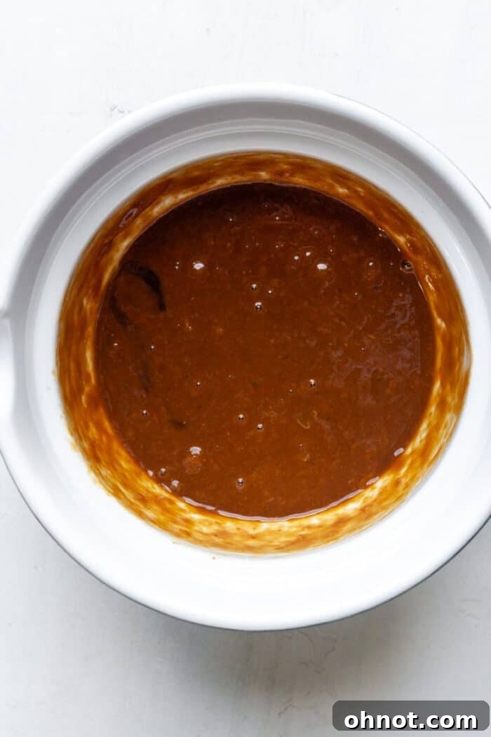 Smooth, orange-colored pumpkin bread batter in a stainless steel mixing bowl.