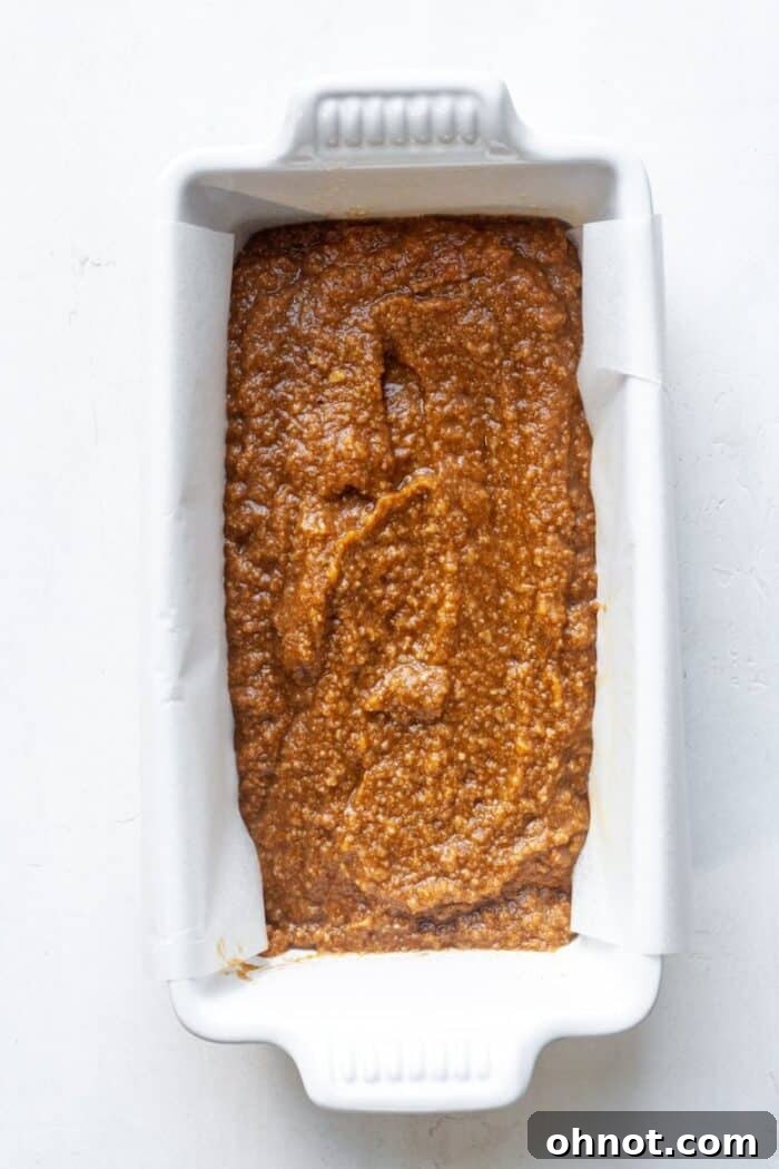 Smooth pumpkin bread batter poured into a parchment-lined loaf pan.