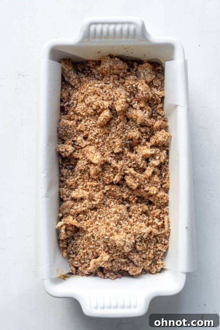 Unbaked pumpkin bread with a generous layer of streusel topping in a loaf pan.