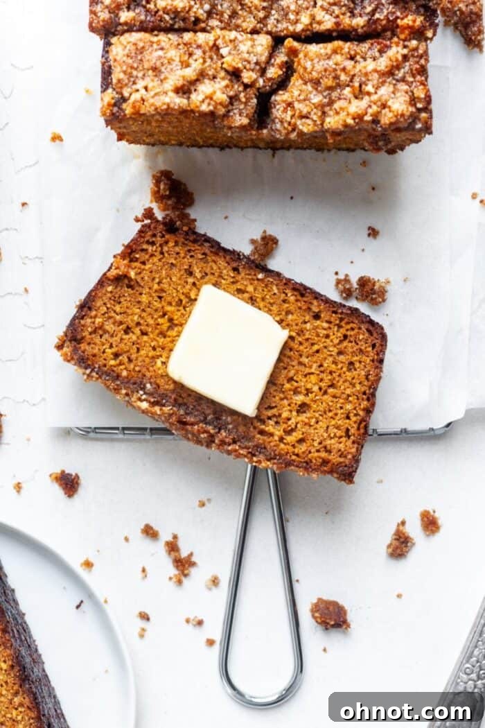 A fresh slice of gluten-free Paleo pumpkin bread topped with a dollop of butter.