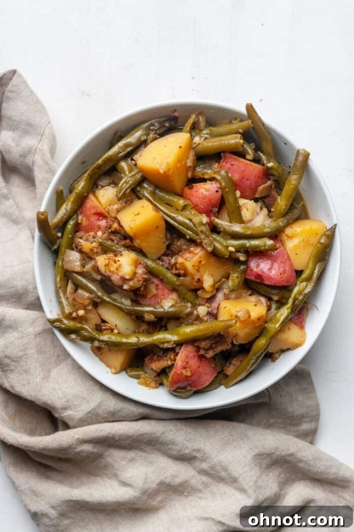 Bowl with green beans and potatoes, garnished with bacon