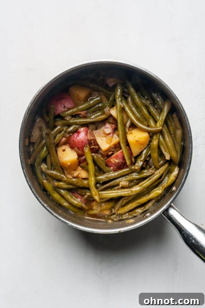 Pot of green beans and potatoes simmering with a lid on