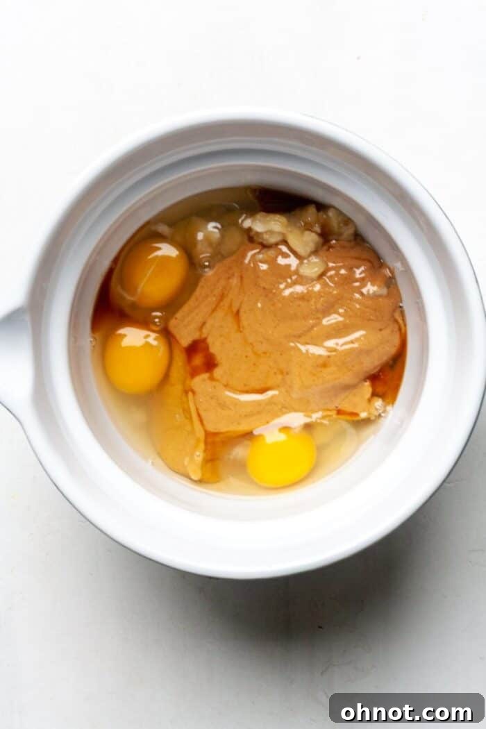 Peanut butter and eggs being mixed in a bowl.