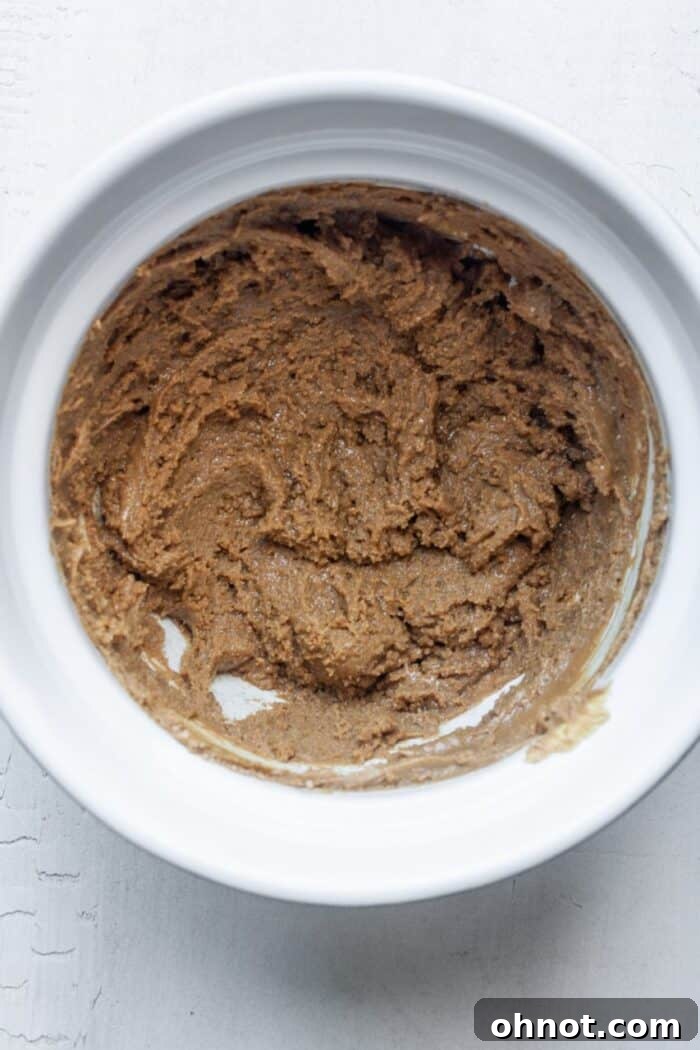 Sunflower butter and brown sugar being mixed in a bowl to form cookie dough.