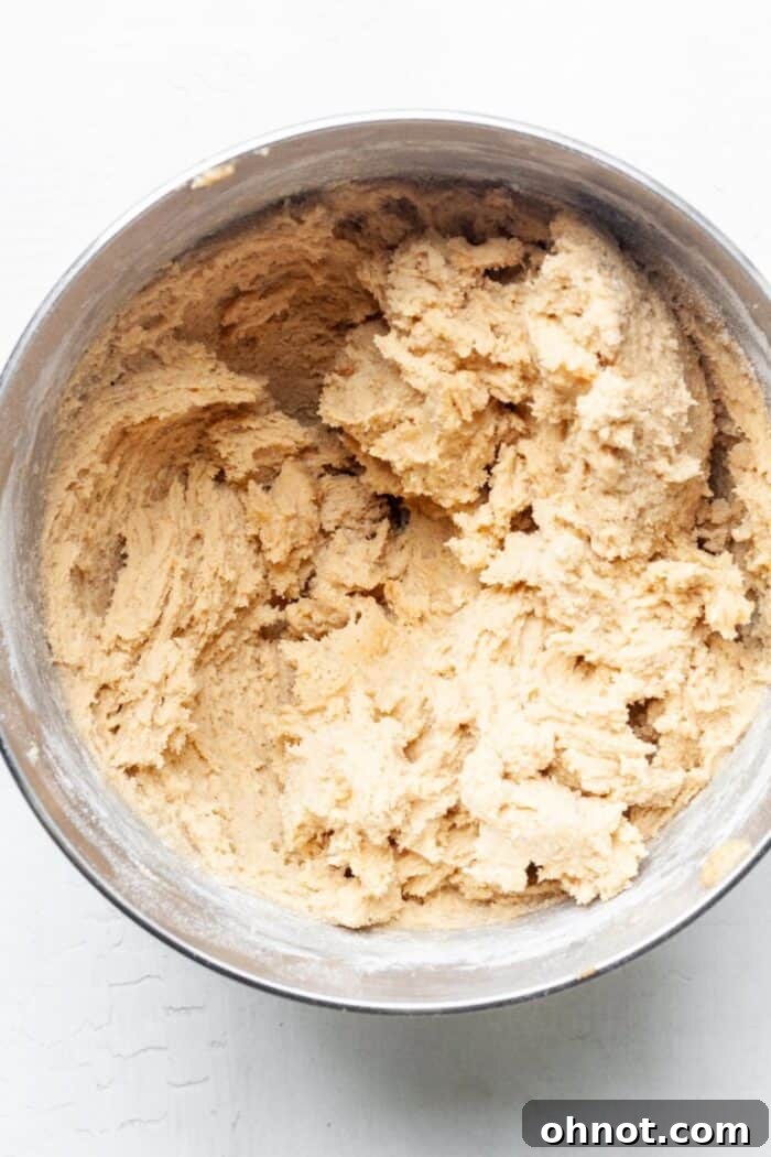 Thick, well-mixed peanut butter cookie dough in a mixing bowl after dry ingredients are added.