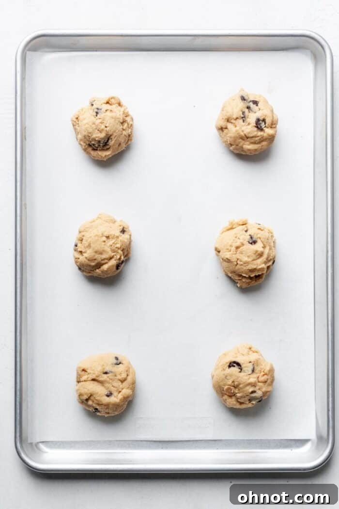 Evenly scooped balls of peanut butter cookie dough placed on a parchment-lined baking sheet.