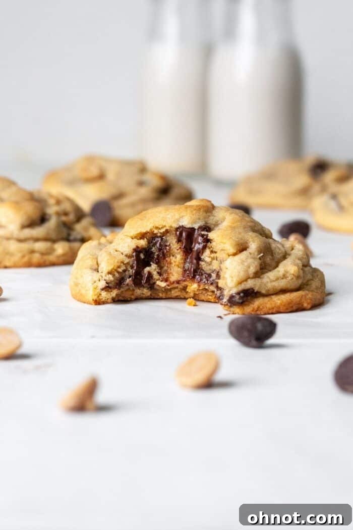 Assorted gluten-free cookies, including a peanut butter cookie with chips, on a white surface.