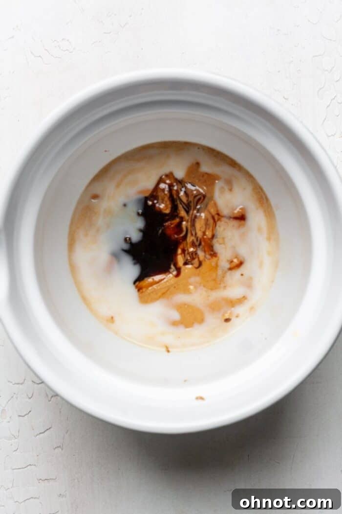 Mixing bowl with almond milk and peanut butter being combined, showing the initial wet ingredient mixture.