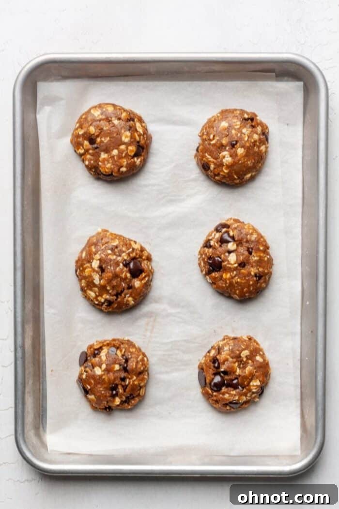 Peanut butter dough balls on a baking pan, flattened slightly before baking.
