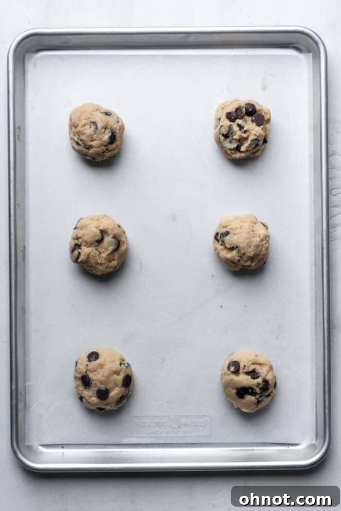 Evenly spaced balls of cookie dough on a parchment-lined baking pan, ready for the oven.