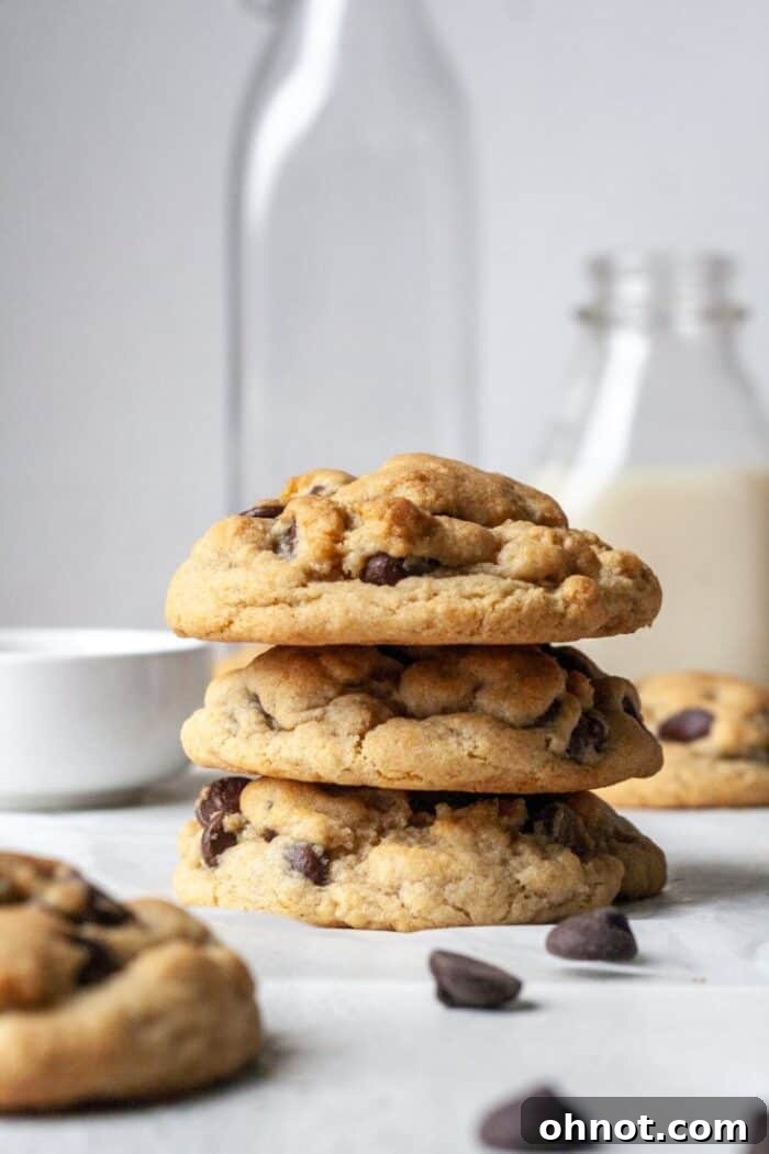 A stack of three perfectly baked eggless chocolate chip cookies, showcasing their golden color and ample chocolate chips.
