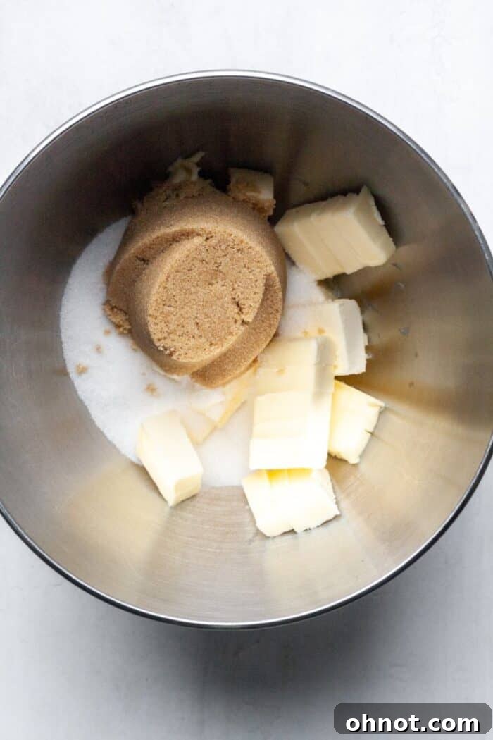 Cold butter, white sugar, and light brown sugar combined in a mixing bowl before creaming.