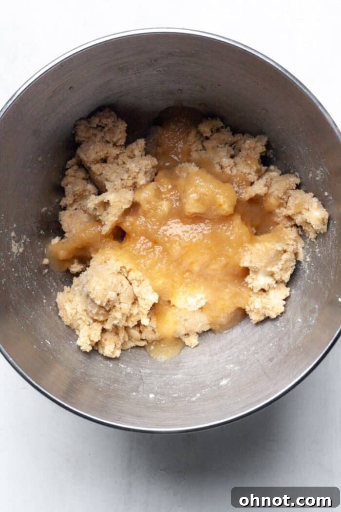 Applesauce added to the cookie dough mixture in a bowl.