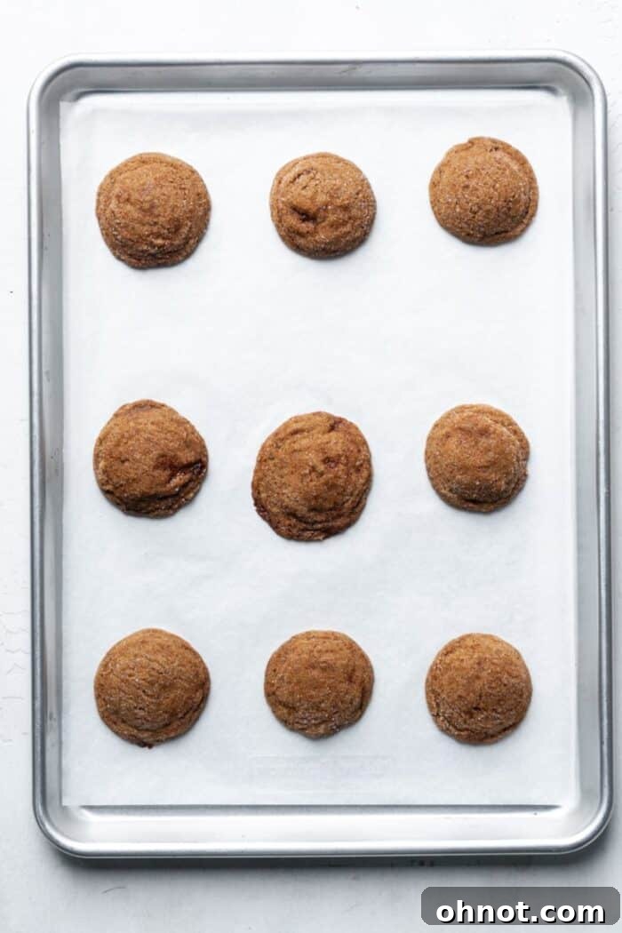 Freshly baked gluten-free ginger cookies on a parchment-lined pan.