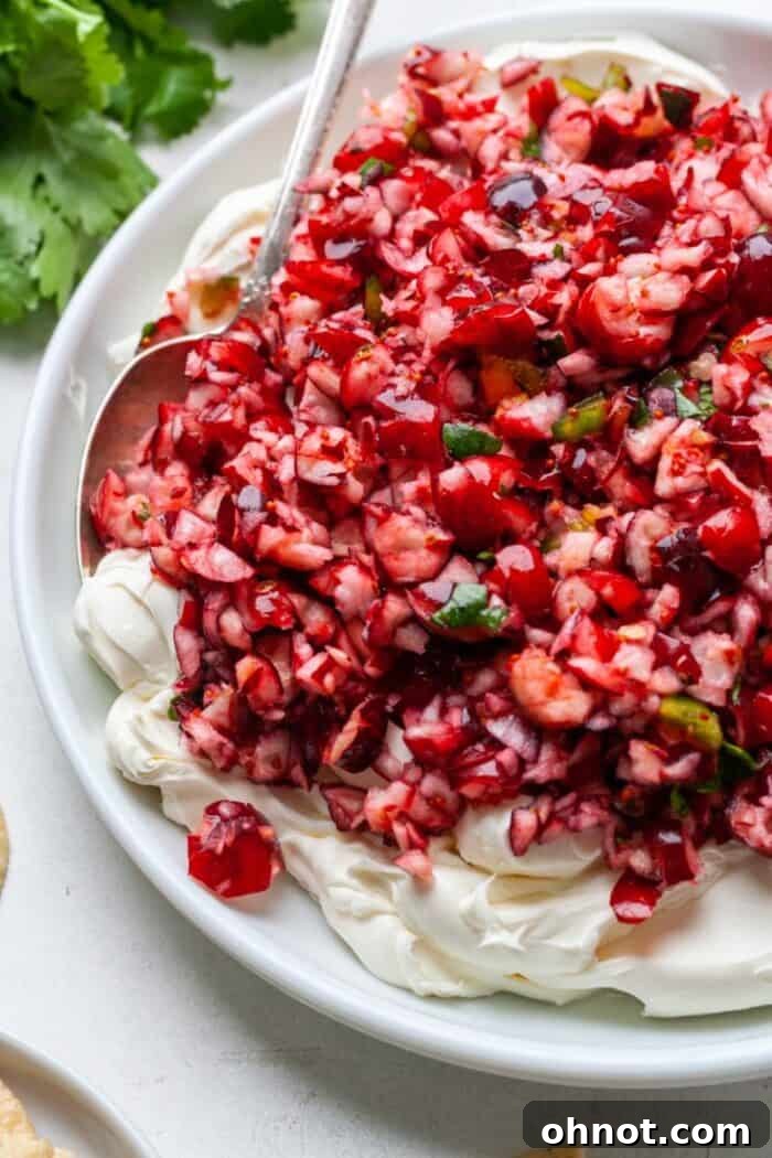 Close-up of cranberry jalapeño dip, showcasing the vibrant red topping and creamy white base