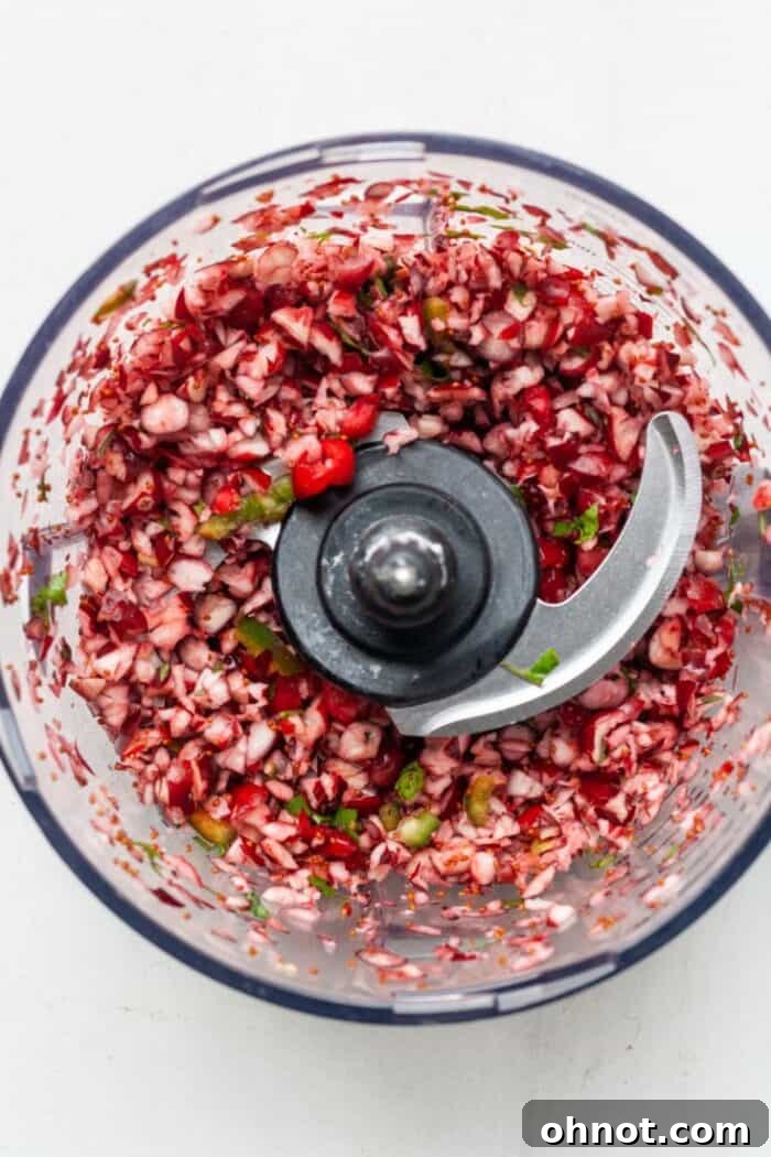 Coarsely chopped cranberry, jalapeño, and cilantro mixture in a food processor bowl