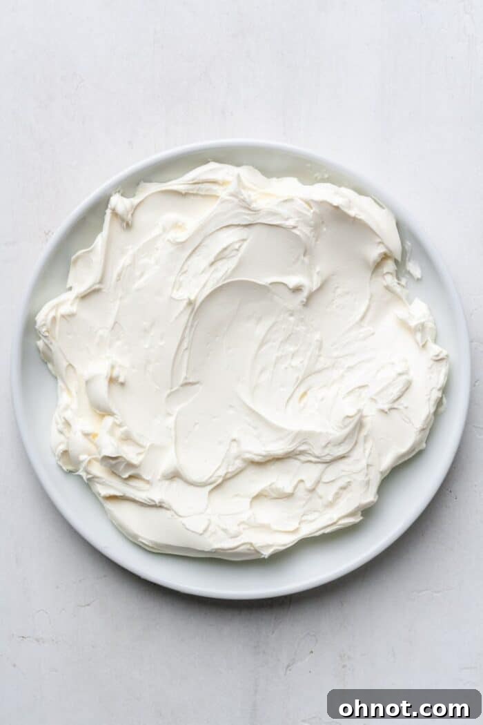 Softened cream cheese spread evenly on a white serving plate, ready for topping