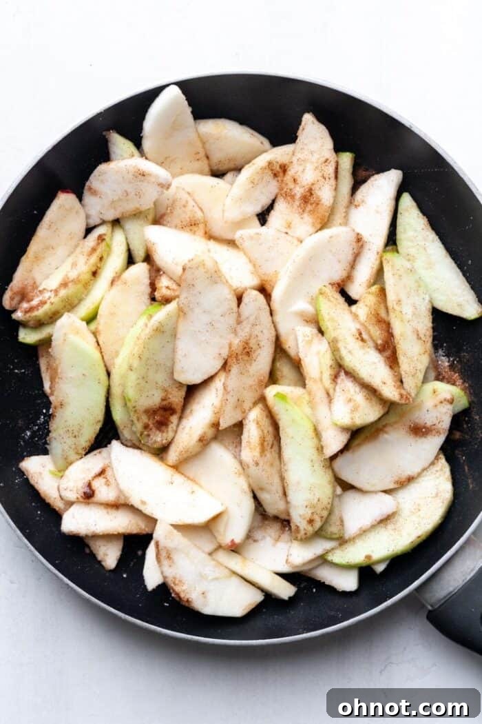 Cinnamon apples simmering in a black skillet