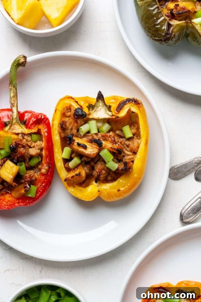 Two halves of stuffed bell peppers on a white plate, showcasing the chicken and pineapple filling.