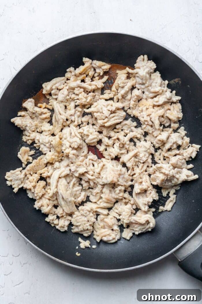 Ground chicken cooking in a skillet on the stove.