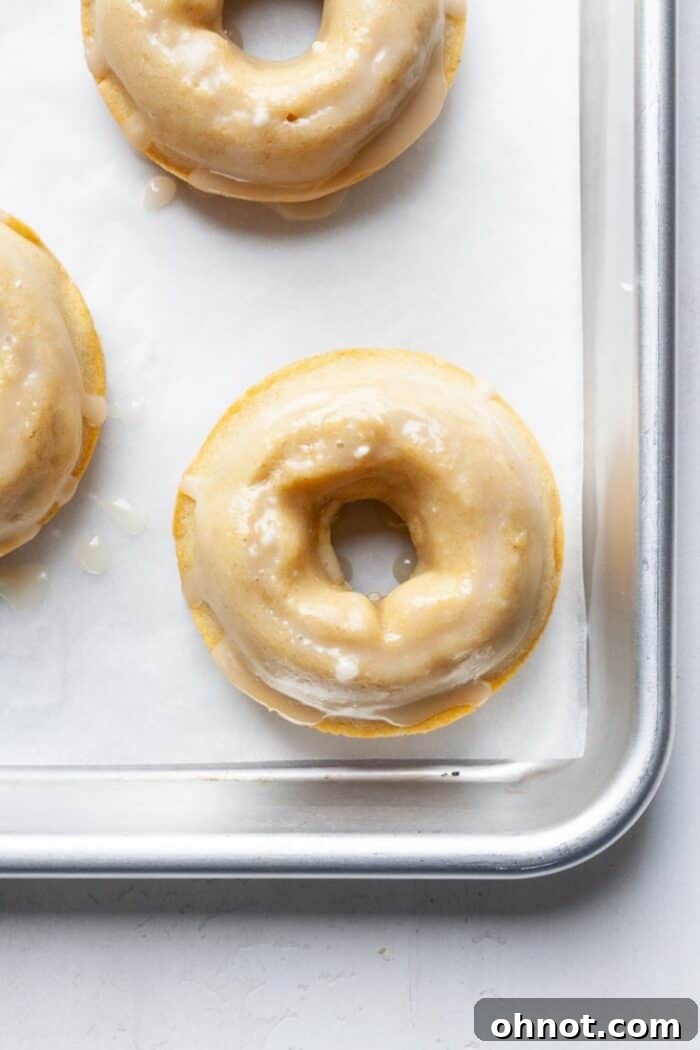 A batch of baked gluten-free donuts cooling on a wire rack, waiting for their sweet vanilla glaze.