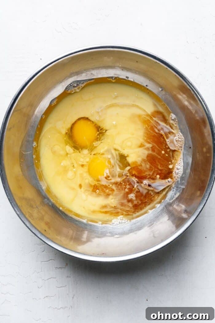 Fresh eggs and milk being mixed in a bowl, forming the liquid base for the donut batter.