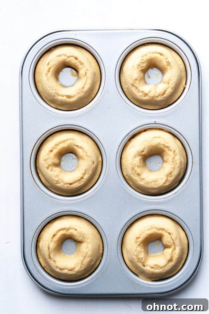 Freshly baked vanilla gluten-free donuts still in the pan, showing their perfect golden rise.