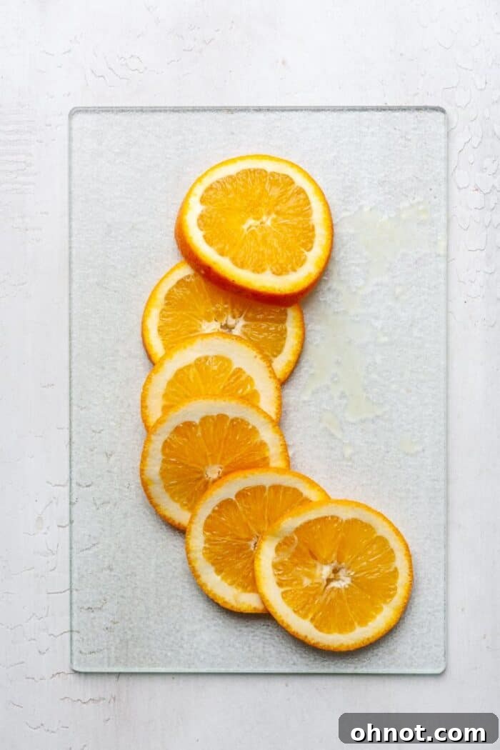 Perfectly sliced oranges arranged on a wooden cutting board.