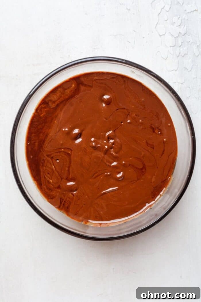 Smooth, melted dark chocolate and coconut oil in a glass bowl.