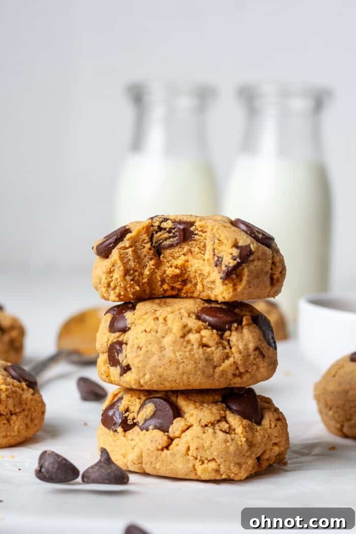 Stack of freshly baked protein chocolate chip cookies with melted chocolate chips visible, garnished with a sprinkle of sea salt.