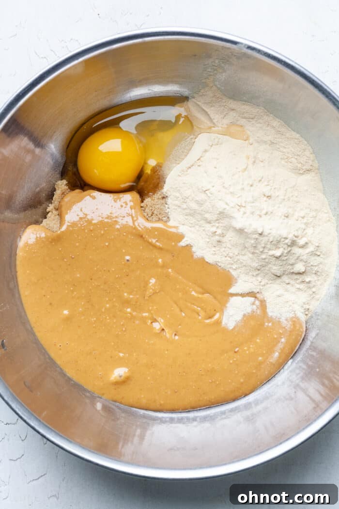 Creamy peanut butter and a whole egg ready to be mixed in a bowl, demonstrating the first wet ingredients.