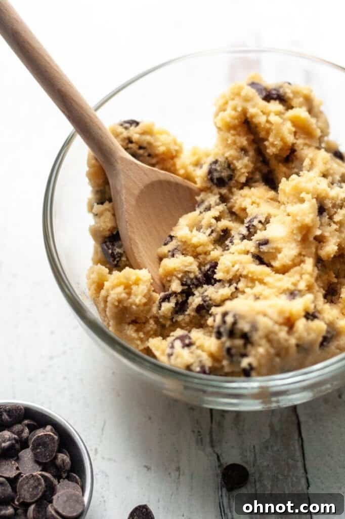 Two bowls of gluten-free edible cookie dough, with one featuring a spoon ready for tasting.