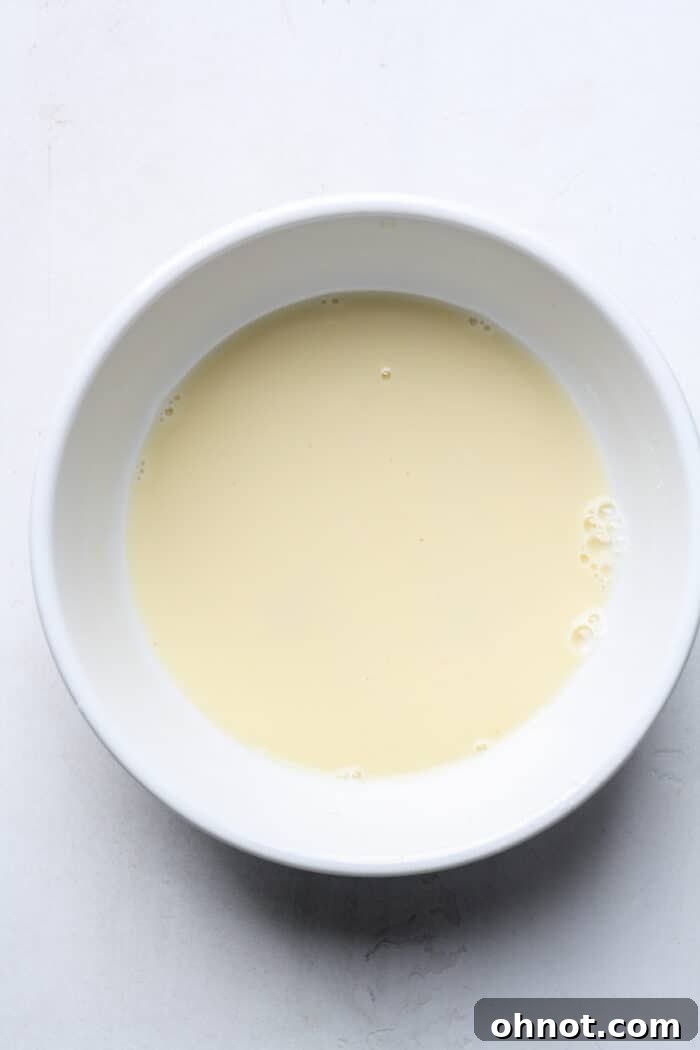 A bowl containing a whisked egg and milk mixture, ready for breading.