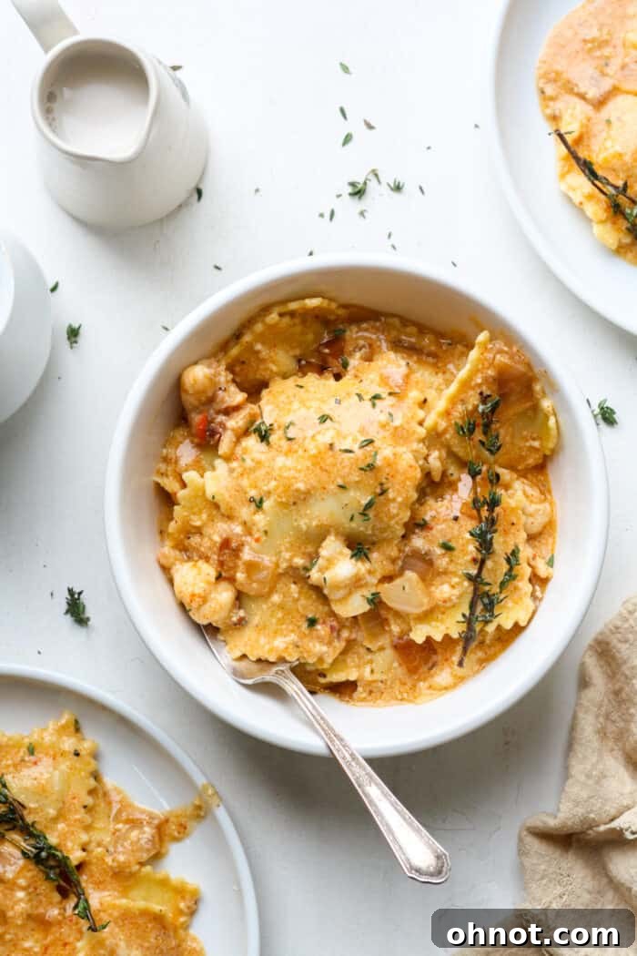 Creamy lobster ravioli sauce served in a white bowl, garnished with fresh thyme.