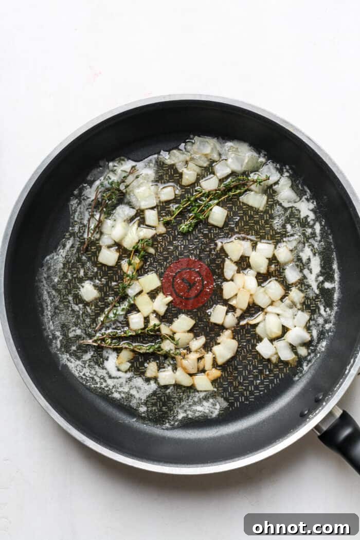 Melted butter with softened onions and thyme in a skillet.
