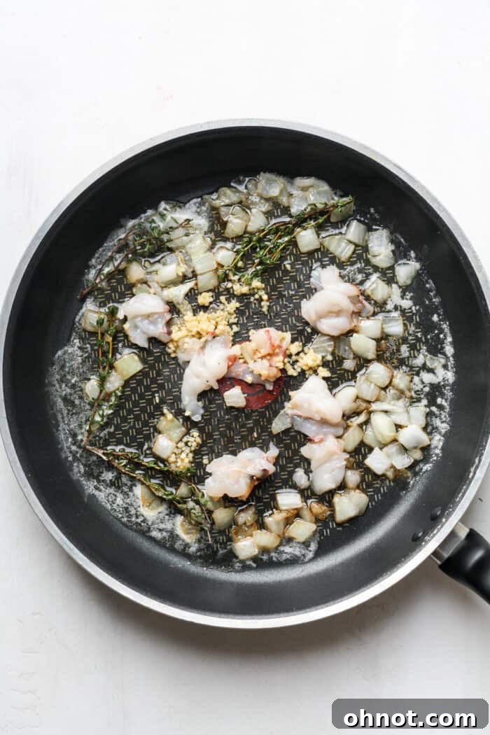 Bite-sized lobster pieces and minced garlic added to the skillet.