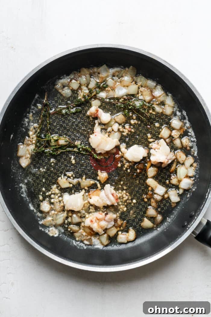 Lobster meat infused with thyme and butter in a pan.