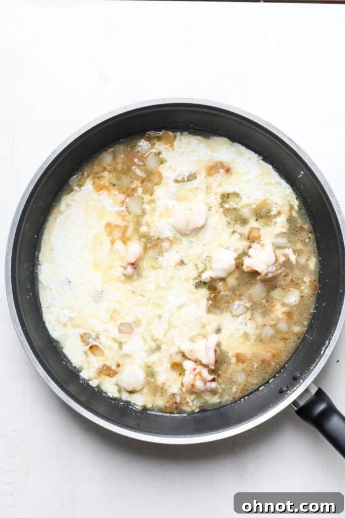 Heavy cream being poured into the skillet with other ingredients.