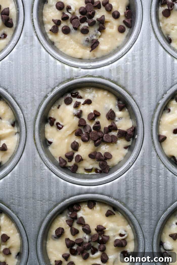 Muffin batter neatly scooped into a greased muffin pan, ready for baking.