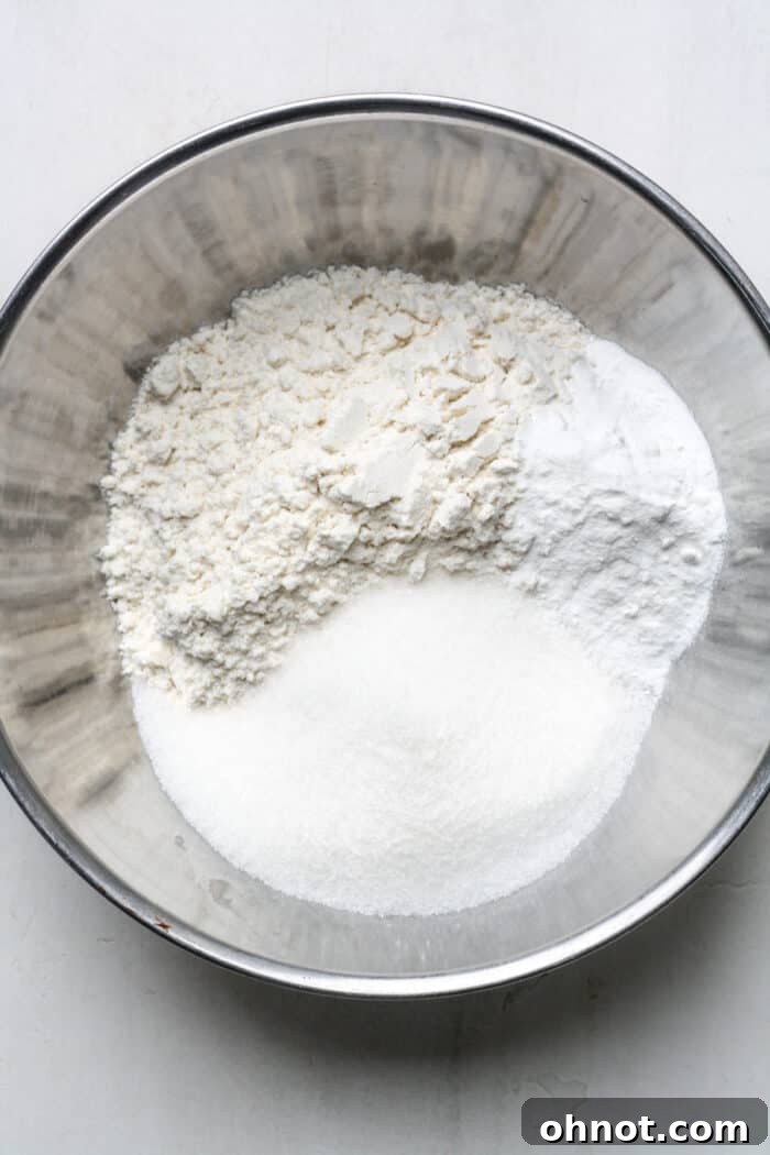 Gluten-free flour, sugar, and baking powder mixed in a bowl.