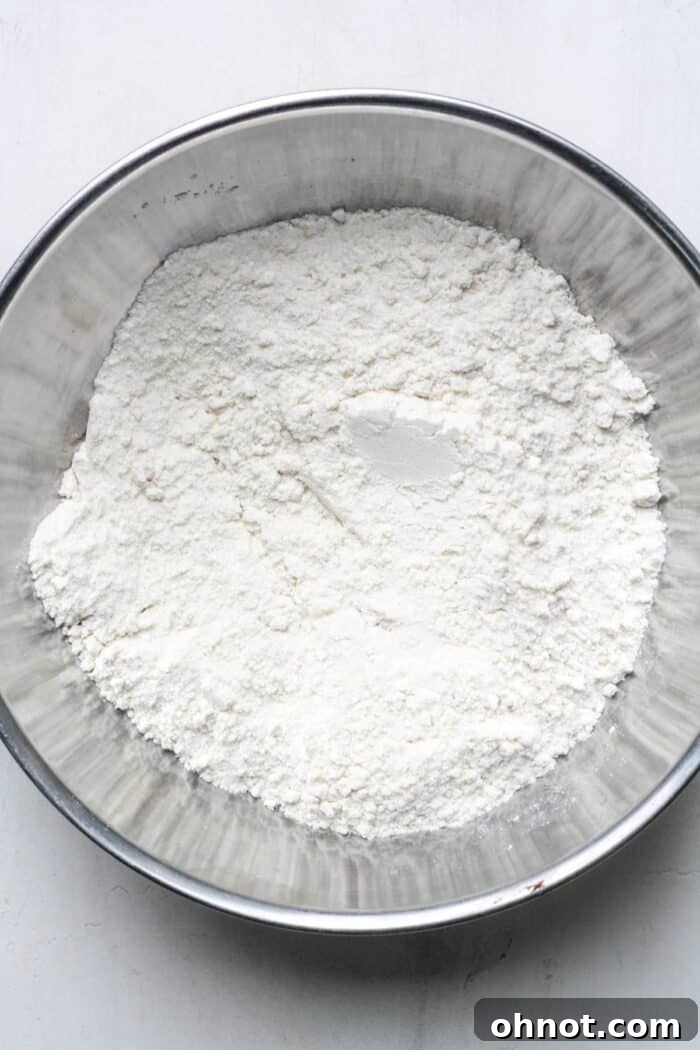Close-up of flour, sugar, and baking powder being stirred in a bowl.