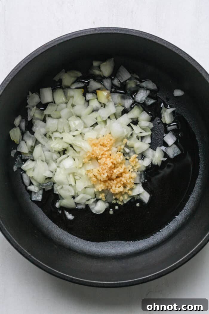 Diced onions and minced garlic gently sizzling in olive oil in a Dutch oven.