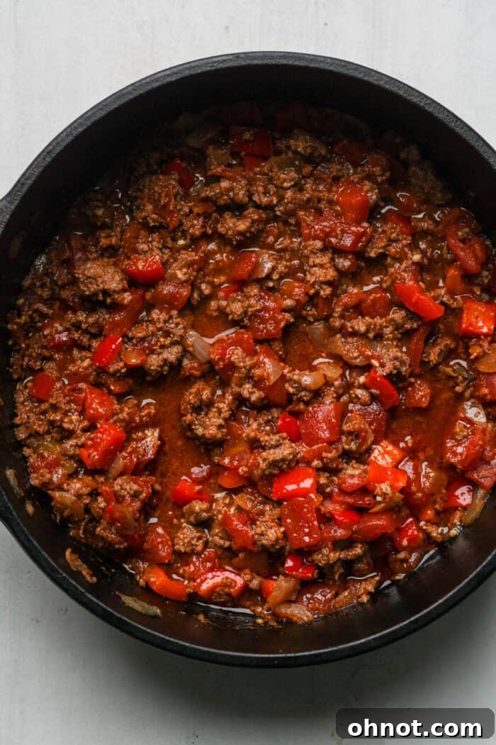 Chili mixture actively boiling in a large pot, with steam rising.