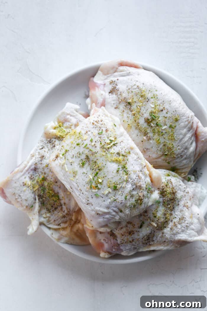 Seasoned chicken thighs on a plate, ready for bagging