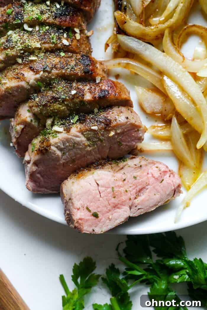 Medium-cooked sous vide pork tenderloin, perfectly sliced and presented on a white plate.