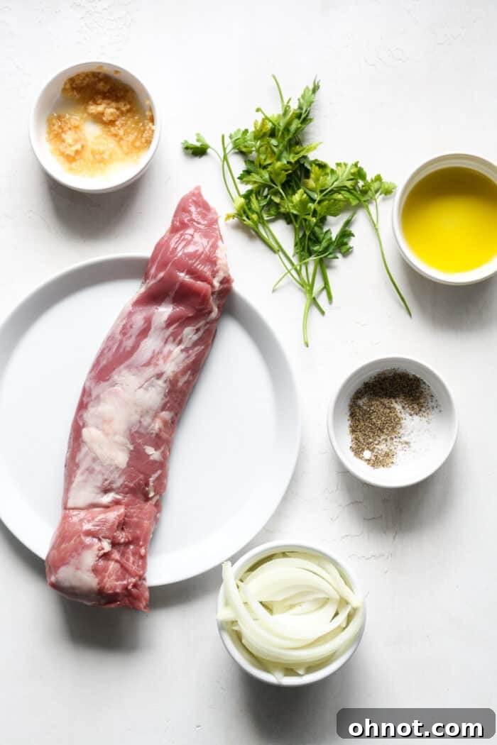 Ingredients for sous vide pork tenderloin laid out on a cutting board, including pork, fresh herbs, salt, pepper, garlic, and onion.