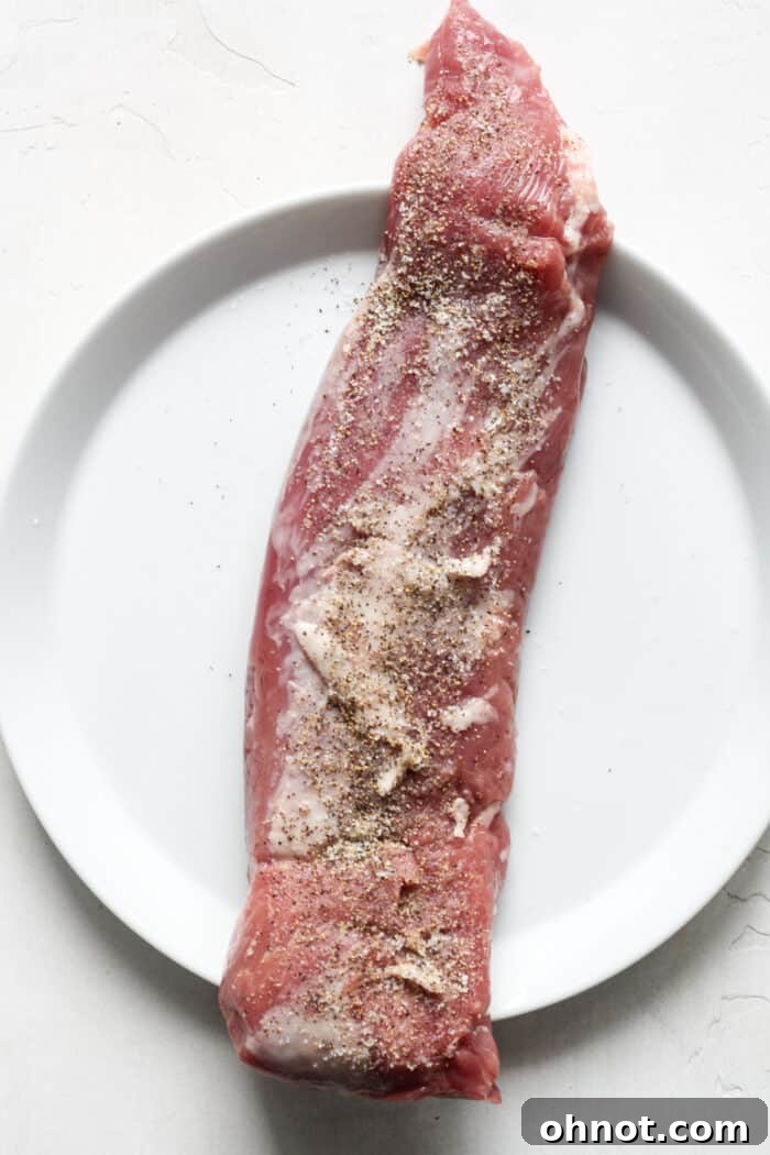 Pork tenderloin seasoned with salt and pepper on a plate.